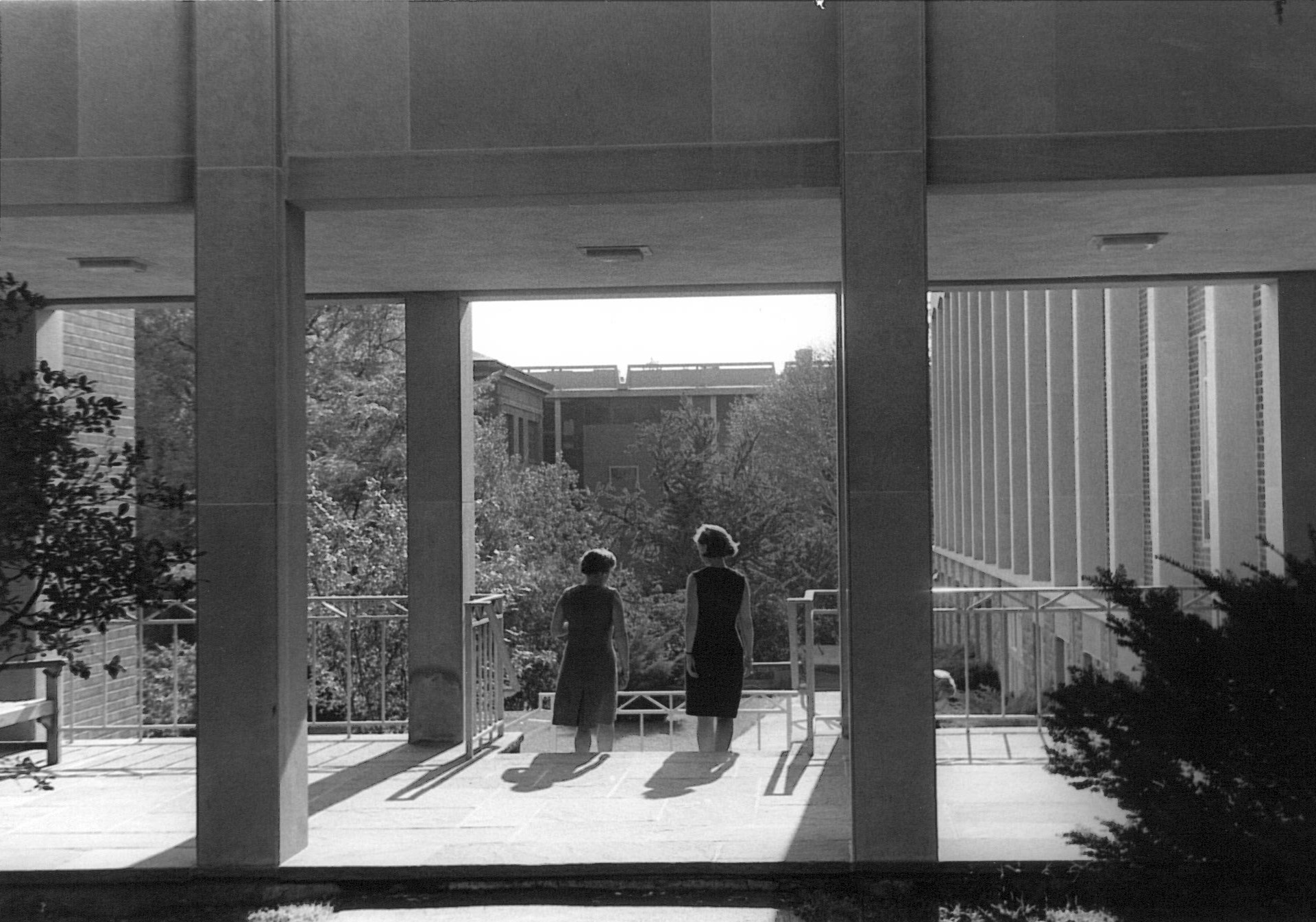 Black and white photo of two students looking out from a balcony