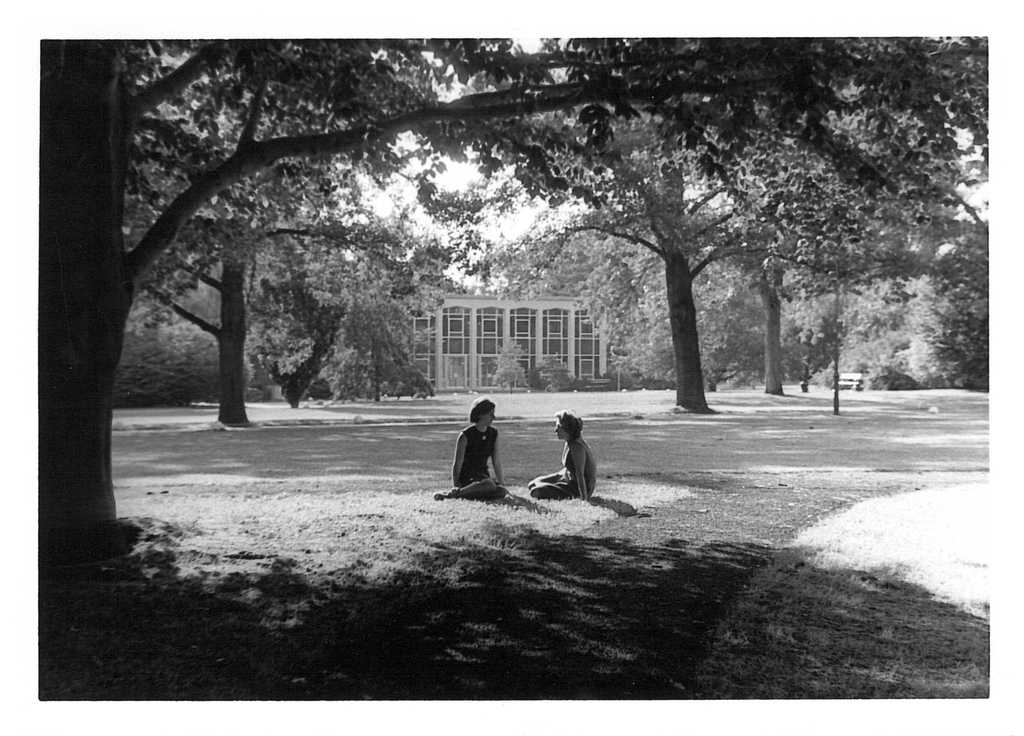 Black and white photo of two people sitting on the lawn
